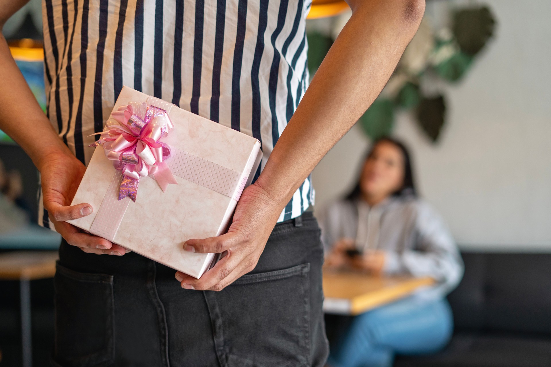 Excited young woman receiving a gift from her boyfriend in a restaurant.