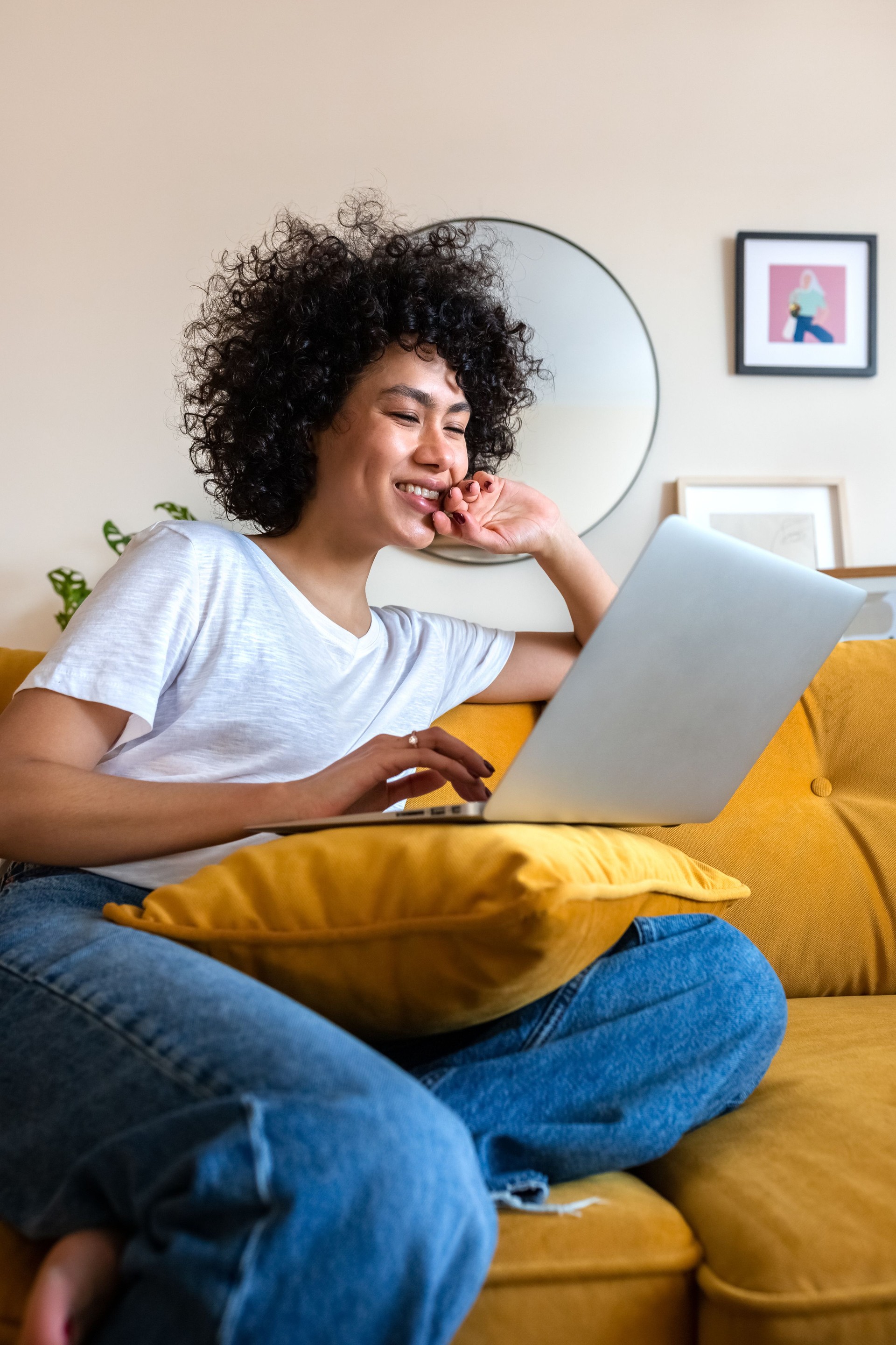 Happy African American woman having fun using laptop at home. Laughing watching funny online videos.